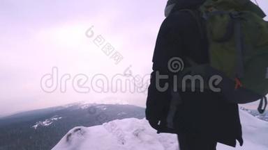 一个年轻人，一个游客，<strong>站在</strong>一座白雪覆盖的山的边缘，欣赏<strong>山顶</strong>。